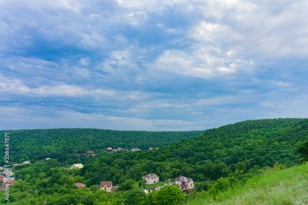Landscape with green meadows and houses under the dark blue sky Landscape with green meadows and houses under the dark blue sky