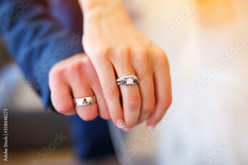 Young married couple holding hands and showing wedding rings
