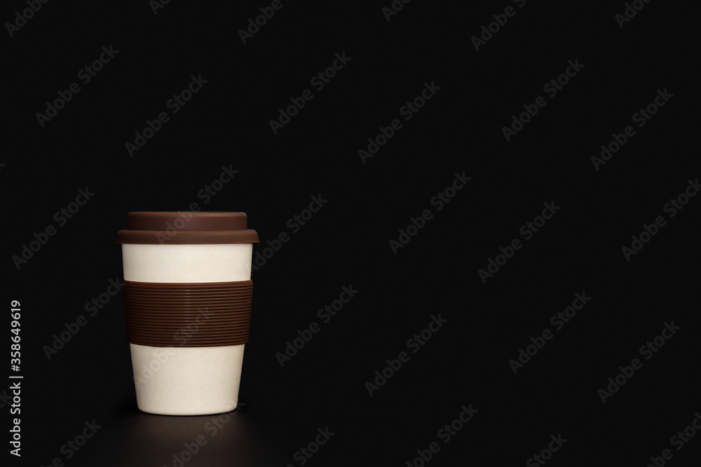 Eco-friendly cup made of bamboo, on a black background. A cup of light shade with a brown lid. Eco-friendly cup made of bamboo, on a black background. A cup of light shade with a brown lid.