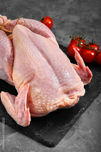 Fresh chicken carcass with tomatoes on a gray background, fresh meat, copy space, photo for grocery stores. dark background