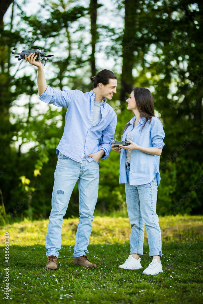 Young pretty couple playing with drone at picnic in green park Young pretty couple playing with drone at picnic in green park