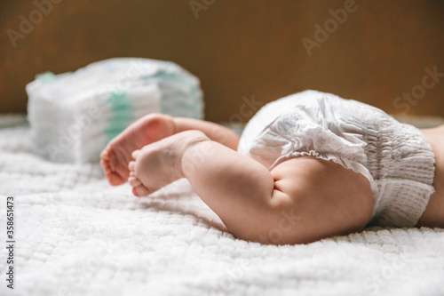 A baby in a diaper at the age of two months and a stack of diapers. How to choose baby diapers