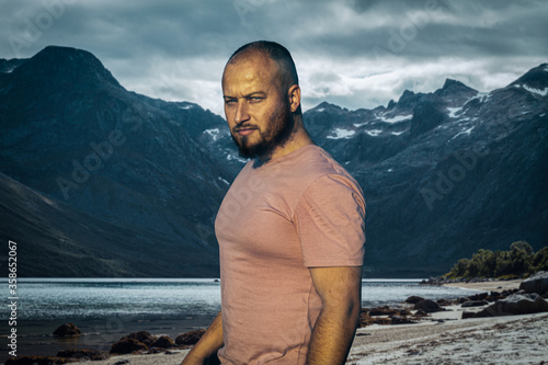 Φωτογραφία severe brutal man on a background of mountains and a fjord