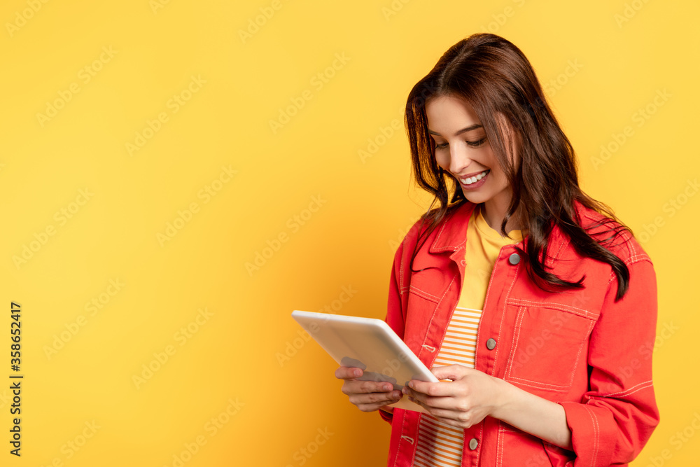 happy young woman using digital tablet on yellow happy young woman using digital tablet on yellow