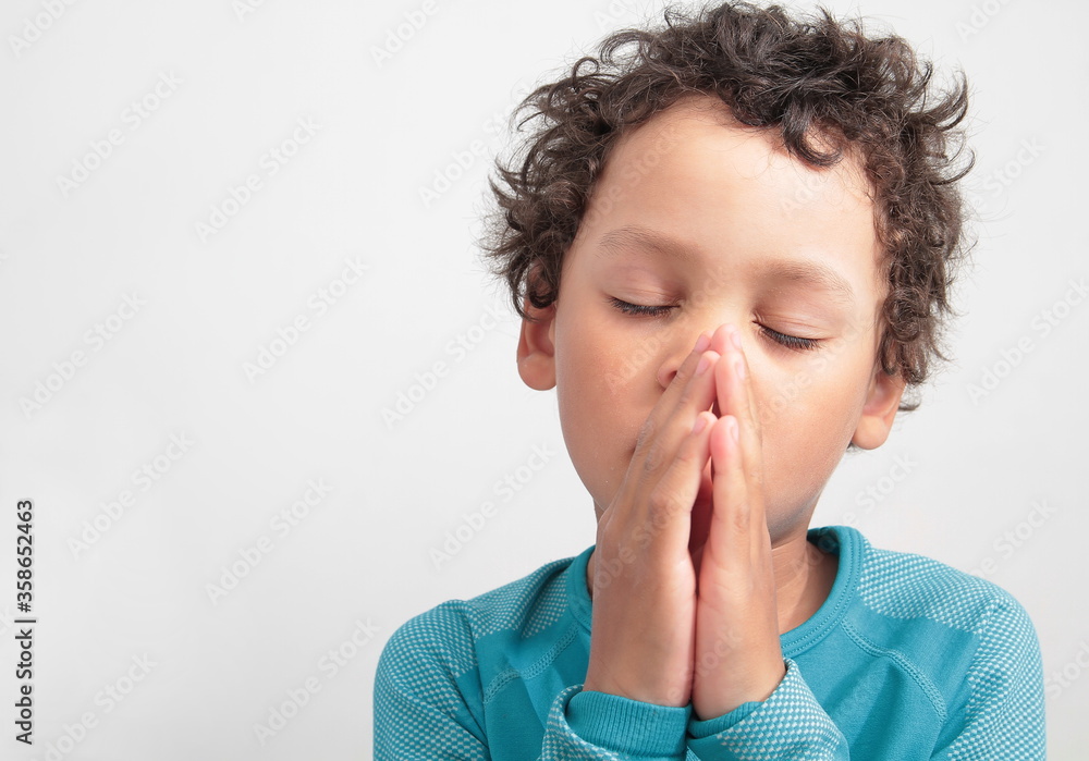 boy praying to God with hands held together with closed eyes boy praying to God with hands held together with closed eyes