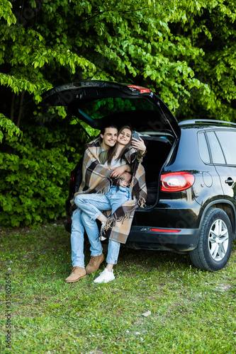 Young people take selfie on phone in car trunk in forest at picnic © F8  \ Suport Ukraine