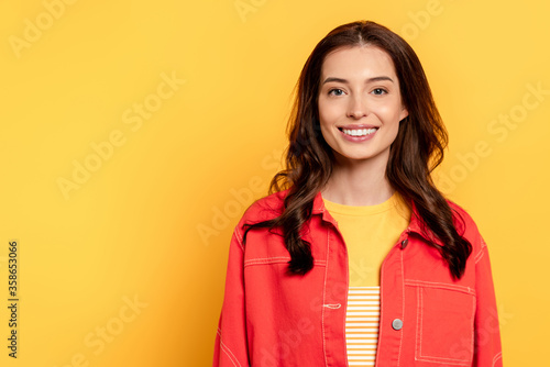 cheerful young woman standing and smiling on yellow © LIGHTFIELD STUDIOS