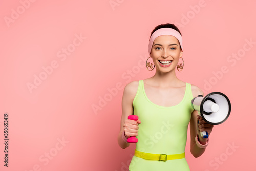 happy sportswoman holding dumbbell and loudspeaker on pink © LIGHTFIELD STUDIOS