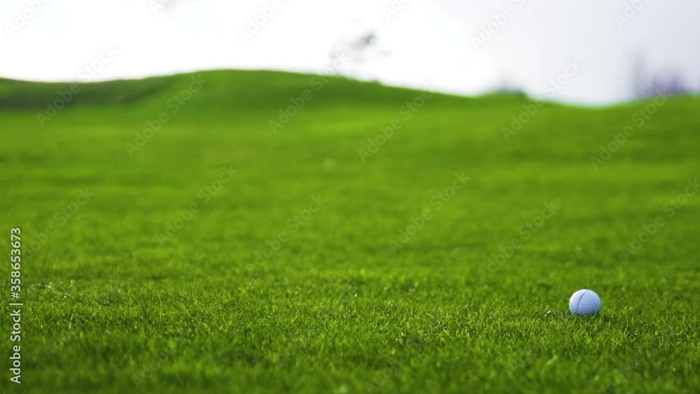 Golfball rolling through the green grass on fairway in slow motion, static shot Golfball rolling through the green grass on fairway in slow motion, static shot