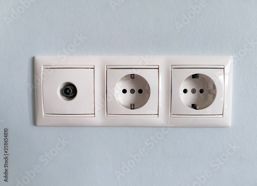 Triple horizontal socket with a connector for an antenna cable on a pale blue painted wall. Design elements for planning the repair of appliances in the house. Socket for TV and set-top box.