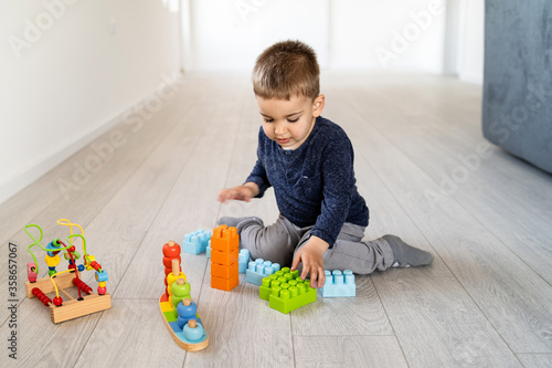 Small boy three or four years old playing on the floor at home - Little caucasian child spending free time alone with brick blocks and creative toys - creativity childhood care growing up concept © Miljan Živković