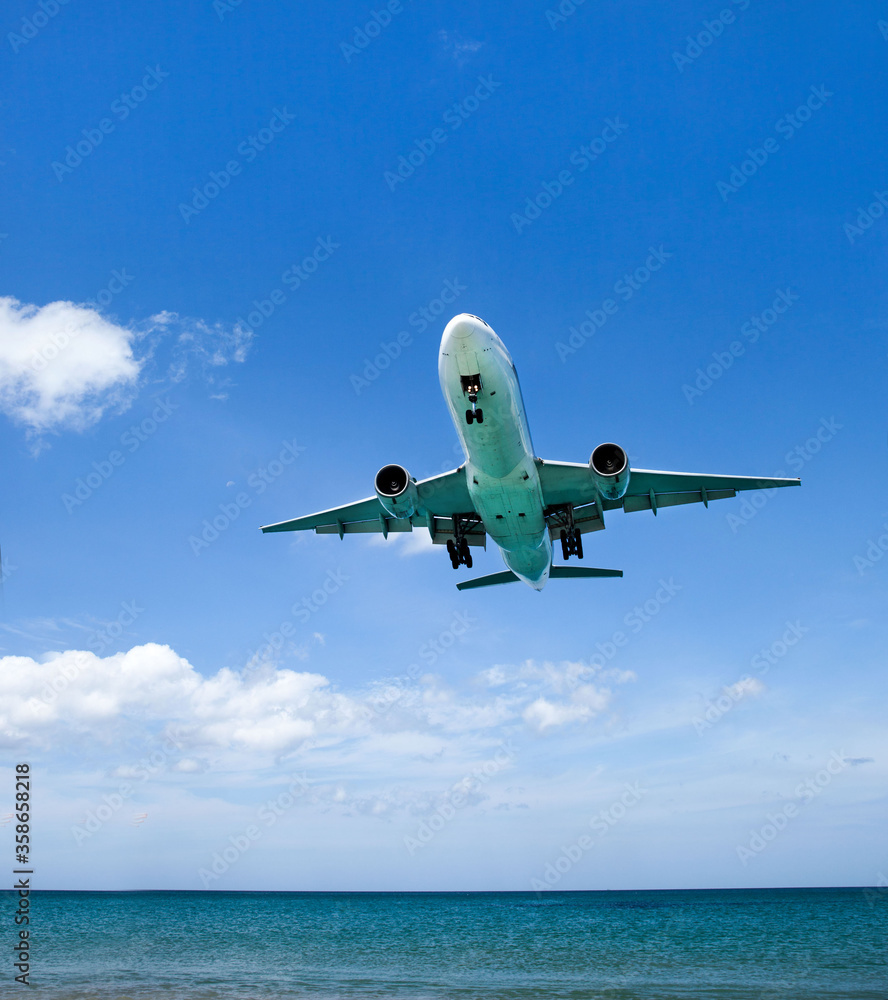 Naklejka premium a passenger plane lands low over the sea, at an airport near the beach on a Sunny day