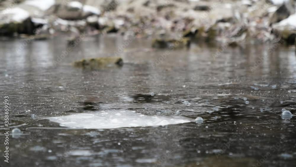 Stone fall on ice with strong splash water breaks frozen surface slow motion. Strong spray frozen river winter closeup. Streams water explode under ice drop rock slow motion. Powerful splashing river