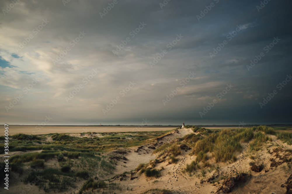 Happy romantic wedding couple on sand dune. Bride and groom standing on sand and embracing. Evening shot with dramatic sky. Wedding day concept. Happy romantic wedding couple on sand dune. Bride and groom standing on sand and embracing. Evening shot with dramatic sky. Wedding day concept.