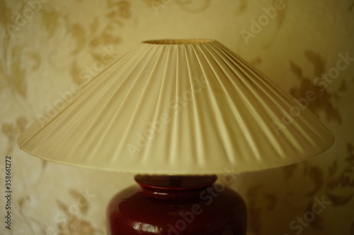 фотографія Table lamp with pleated lampshade in a day room, closeup