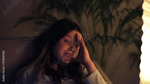 The girl is watching a non-interesting, old movie sitting at home on the couch.