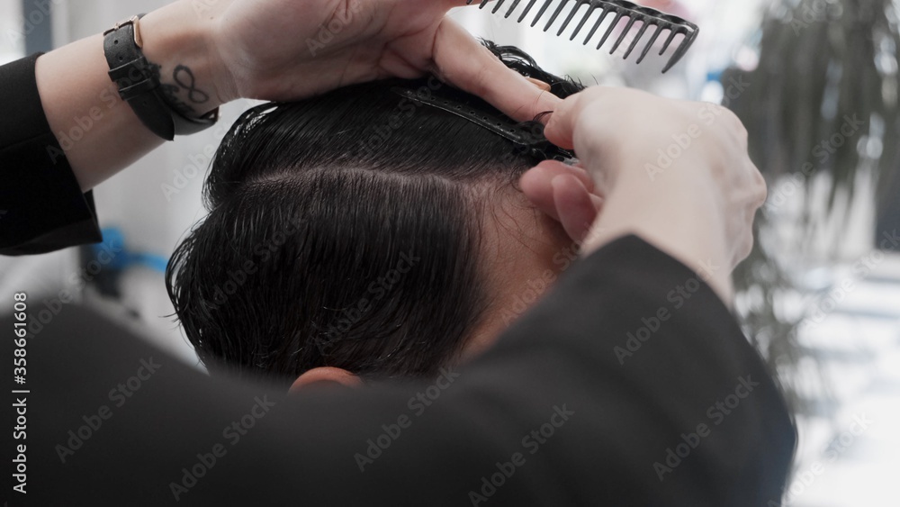 Naklejka premium Professional female hairstylist combing man hair