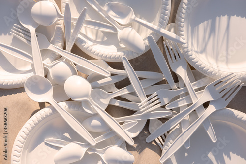 disposable forks, spoons and plates of corn starch on a picnic in nature. biodegradable dishes. Replacing plastic with environmentally friendly materials. close-up. shadow from the grass. natural ligh