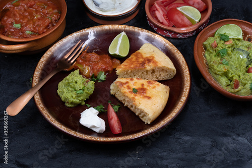 Mexican skillet cornbread served with tomato salsa and guacamole, sour cream on clay dish