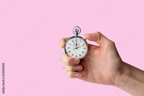 stopwatch hold in hand, button pressed, pink background