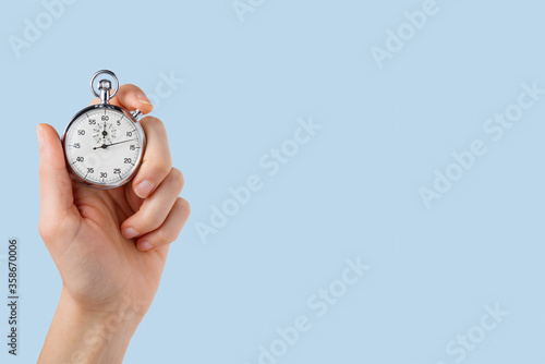 stopwatch hold in hand, button pressed,lighr blue background photo