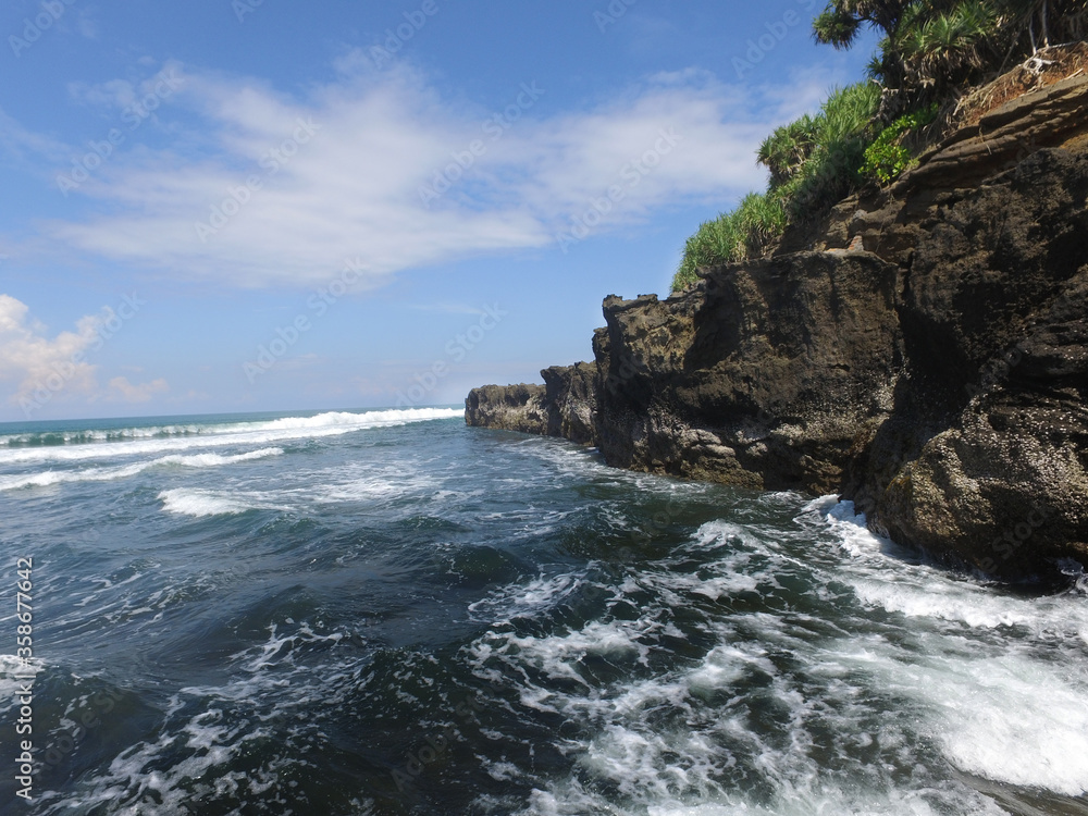 Waves from the ocean to the rock cliffs of the beach on the coast of Bali. Waves from the ocean to the rock cliffs of the beach on the coast of Bali.