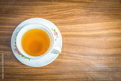 Camomile tea in the white cup placed on the wooden table