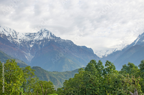The peaks of the mountains of Nepal among the trees are the landscape of the Himalayas 