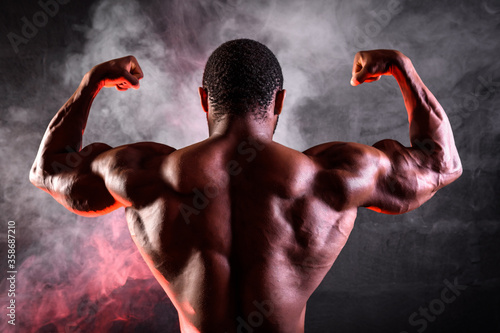 African American male athlete posing demonstrating developed muscles of the back and arms © thomsond