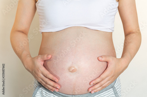 The pregnant woman touches her belly.