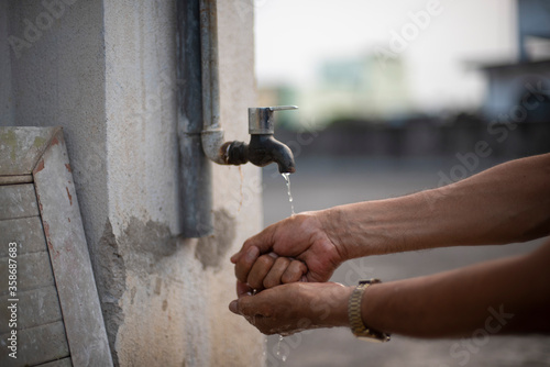 A person washing hands in tap water using sanitizer to prevent corona virus. Indian lifestyle, covid 19, pandemic