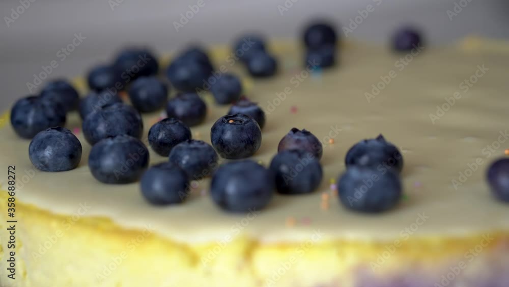 Male hand sprinkling colorful sprinkles on top of blueberry cheesecake. Male hand sprinkling colorful sprinkles on top of blueberry cheesecake.