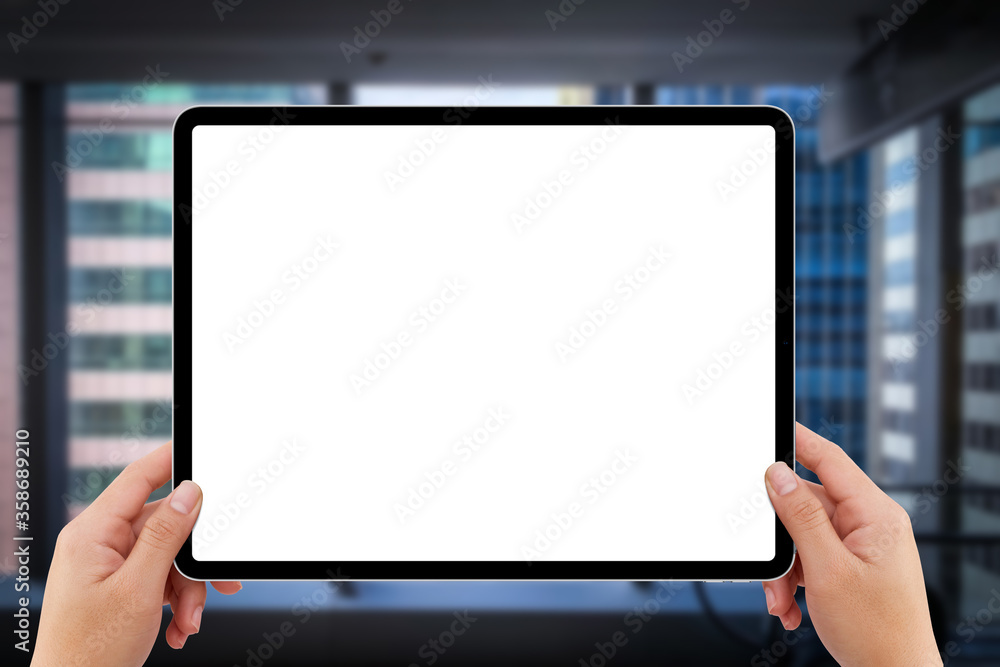 two hands holding white screen mockup tablet computer in indoor shopping mall two hands holding white screen mockup tablet computer in indoor shopping mall