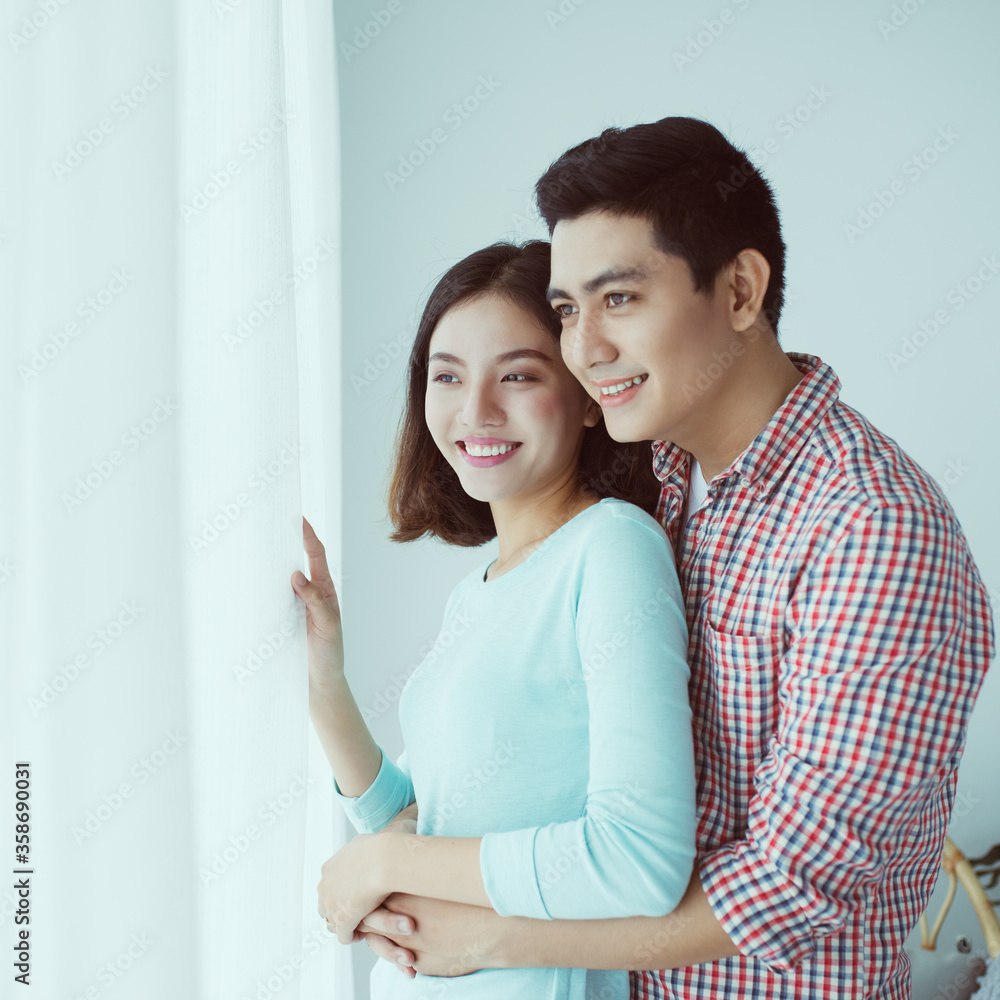 Young Asian Couple Embrace in Modern Apartment behind the window. Young Asian Couple Embrace in Modern Apartment behind the window.
