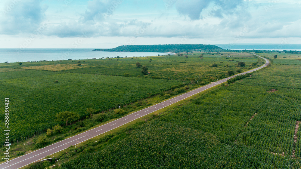 Aerial view of the road between corn field with beautiful beach and sea in Samota, Sumbawa, Indonesia
