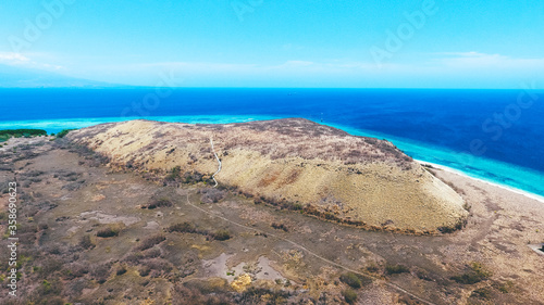 Beautiful summer island with dry grass. Paserang Island in West Sumbawa  Indonesia. The yellow land with small hill and blue sky. Aerial image captured by drone.