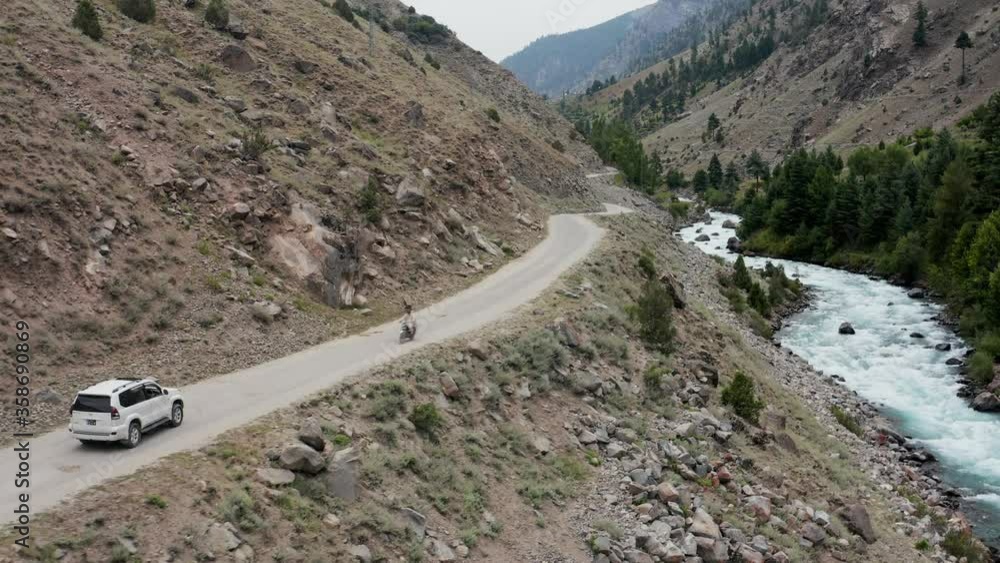 SUV driving along Wild River in Valley, Pakistan, Aerial SUV driving along Wild River in Valley, Pakistan, Aerial