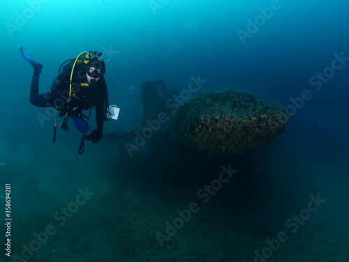 wreck dive underwater fish around ship wreck metal on ocean floor with scuba divers 