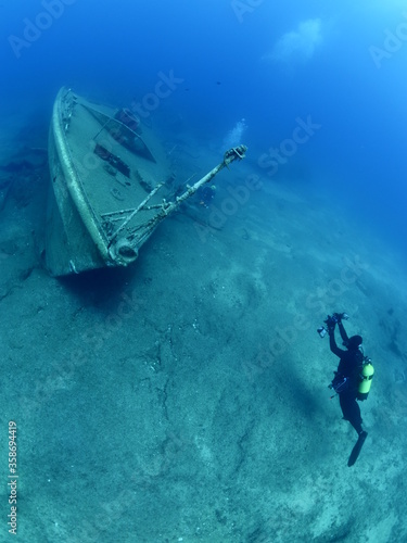wreck dive underwater fish around ship wreck metal on ocean floor with scuba divers 