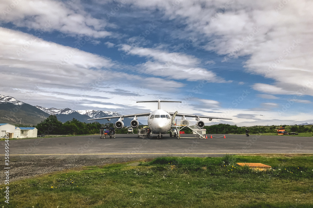 Fototapeta premium Plane at the landing pad of the Puerto Williams airport, with amazing blue and cloudy sky, Chile