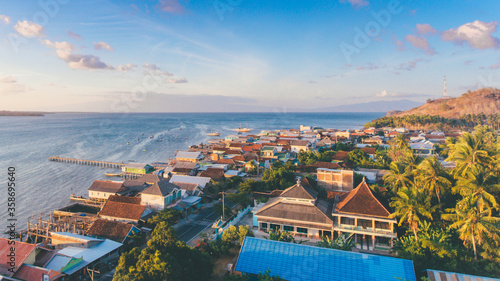 Aerial view of fisherman village in Labuan Jambu, Sumbawa, Indonesia. Traditional house with wooden pier on sea water with blue sky