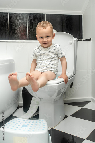 Baby learning toilet. Stomach ache child. A toddler confronts the challenge that awaits him in learning how to use the toilet photo
