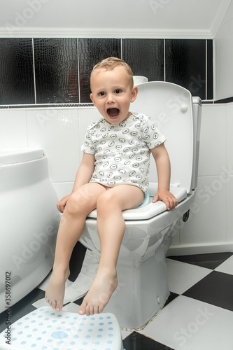 Baby learning toilet. Stomach ache child. A toddler confronts the challenge that awaits him in learning how to use the toilet photo