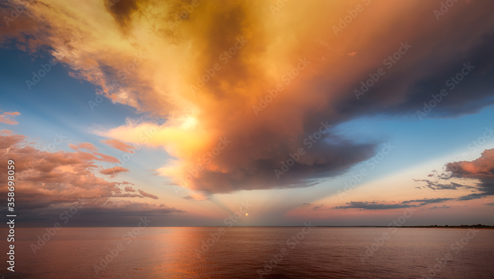 Moon over sea horizon with golden sunset clouds and reflection Moon over sea horizon with golden sunset clouds and reflection