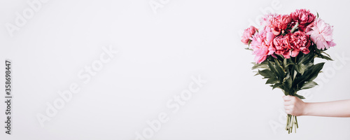 Slika na platnu Female hand holds beautiful bouquet of peonies