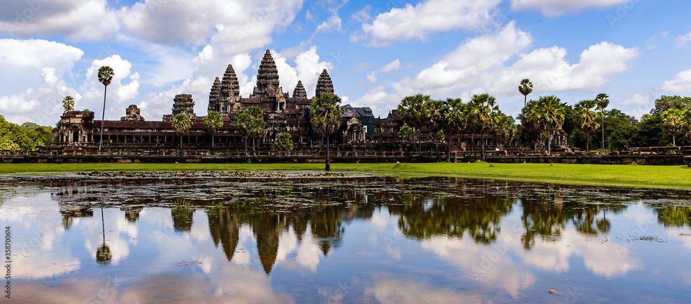 Naklejka premium It's Angkor Wat (Temple City) and its reflection in the lake, a Buddhist, temple complex in Cambodia and the largest religious monument in the world. View from the garden