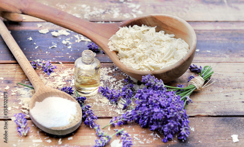 Fotografía spoon full of flakes of soap with essential oil and bunch od lavender flowers an