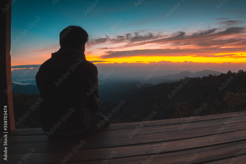 A man sit alone looking at the rising sun at Batu Dulang Village, Sumbawa, Indonesia