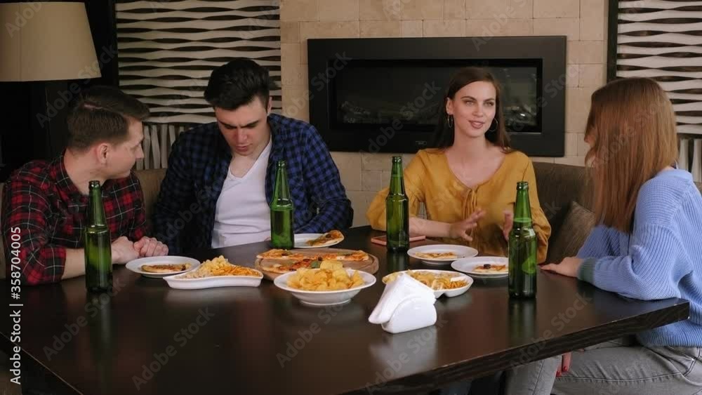 Friends relax in a restaurant, they drink beer, eat chips and pizza and have fun talking. Men talk to each other, and girls talk to each other. Friends relax in a restaurant, they drink beer, eat chips and pizza and have fun talking. Men talk to each other, and girls talk to each other.