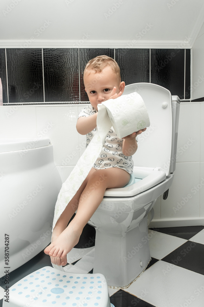 Toddler ripping up toilet paper in bathroom. Stomach ache child Toddler ripping up toilet paper in bathroom. Stomach ache child